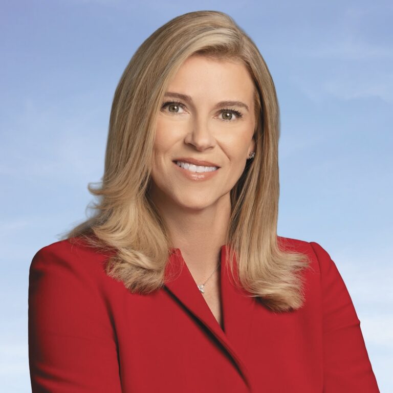 This is an image of Leela Gray, candidate for Florida's 13th Congressional District. She is pictured in a red suit in front of a blue background.